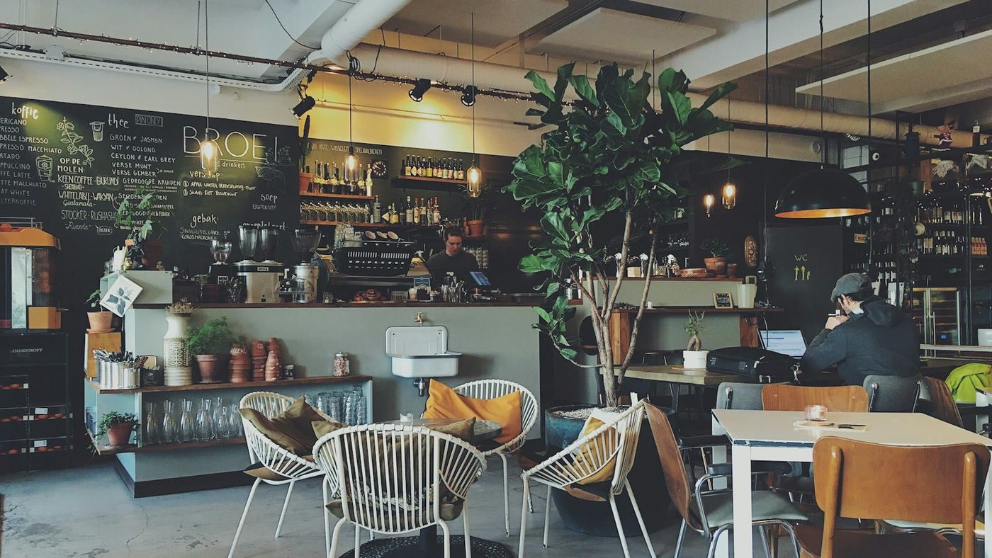 Person working on laptop in a European cafe with a cappuccino